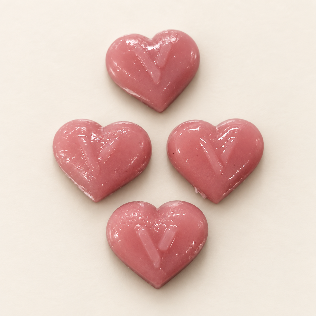 Four smooth pink heart-shaped VEYANA gummies with V imprints